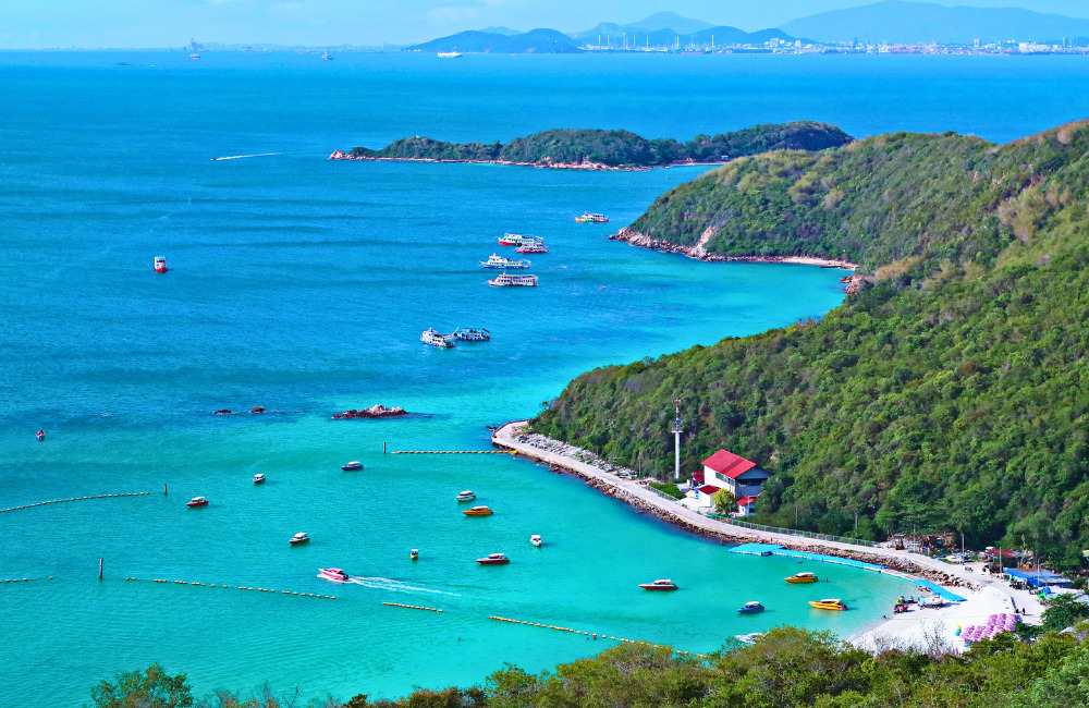 Aerial view of Koh Larn’s turquoise waters, white sand beach, and speedboats, showcasing Coral Island’s natural beauty just off the coast of Pattaya.