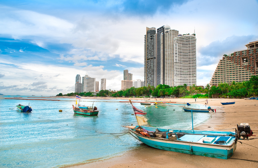 Wong Amat Beach in Pattaya with fishing boats and high-rise hotels – a peaceful and clean beach for travelers seeking quiet moments