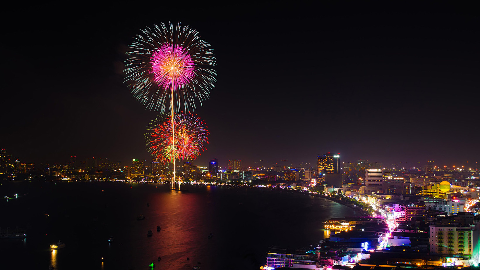 Fireworks illuminating Pattaya Bay with city lights and traffic along Beach Road during the Pattaya Fireworks Festival 2025.