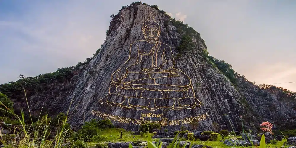 Golden Buddha image carved into the limestone cliff at Khao Chi Chan, a famous cultural attraction in Pattaya