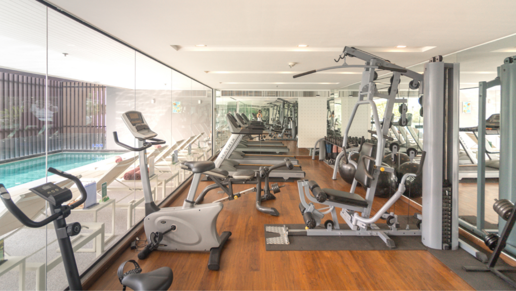Fitness center at Aster Hotel and Residence Pattaya with modern gym equipment and glass view of the swimming pool