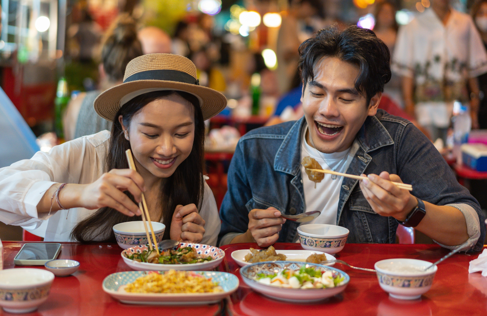 Young couple enjoying Thai street food dinner near Soi Buakhao, close to Hotel Amber Pattaya nightlife.