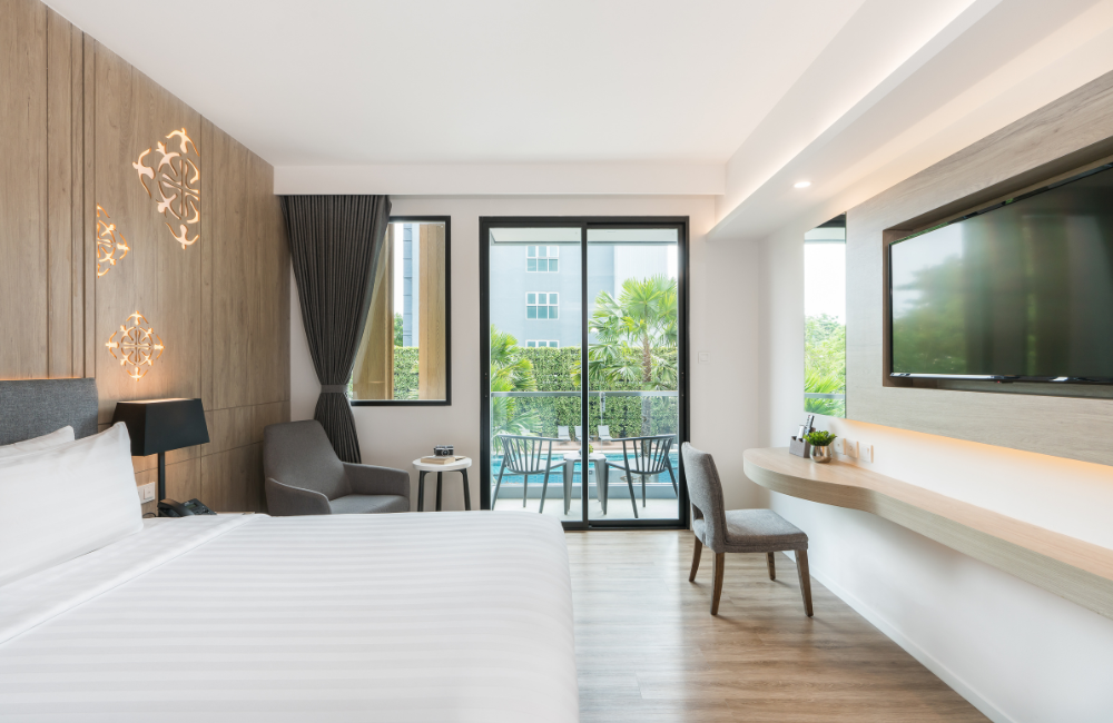 Modern deluxe room at Hotel Amber Pattaya with balcony overlooking the pool, ideal for a relaxing weekend getaway.