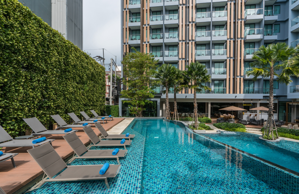 erene poolside atmosphere at Hotel Amber Pattaya with a vertical garden wall and decorative water features.