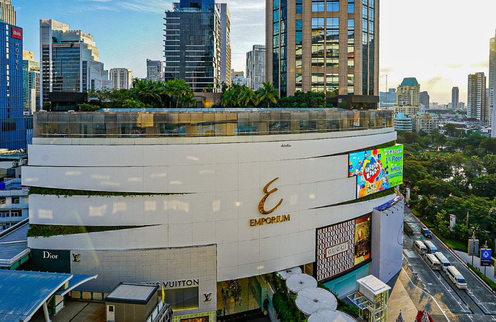 Modern shopping mall in Bangkok with luxury stores and a rooftop garden, set against a vibrant city backdrop.