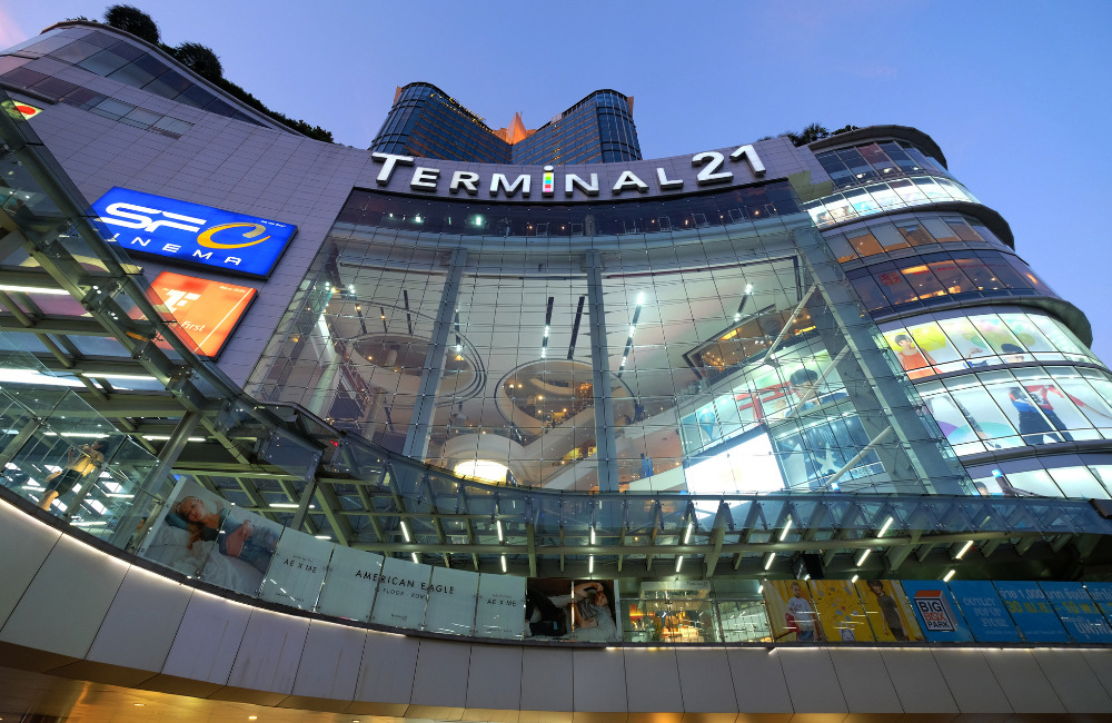 Modern exterior view of Terminal 21 Bangkok shopping mall with glass walls and signage