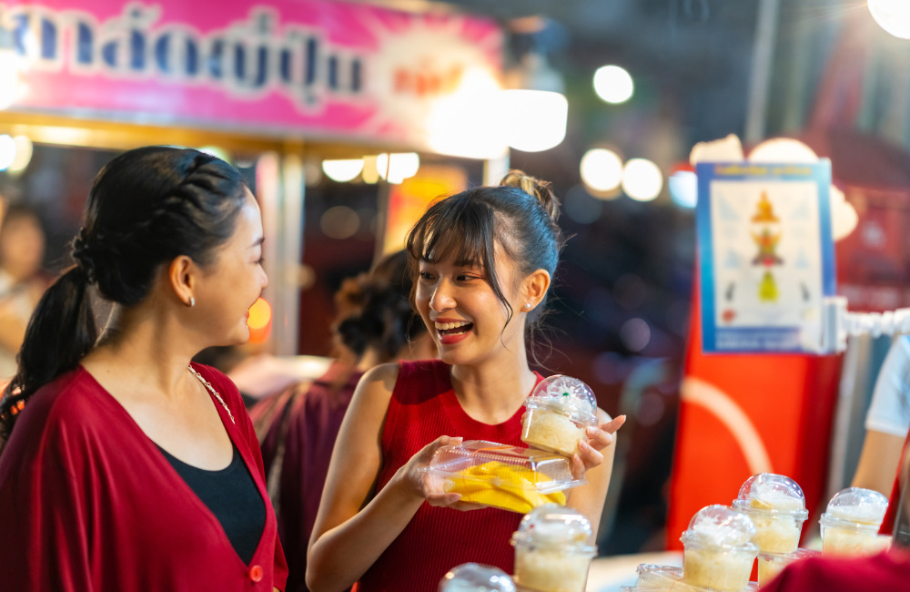 Customer buying mango sticky rice from a night market stall