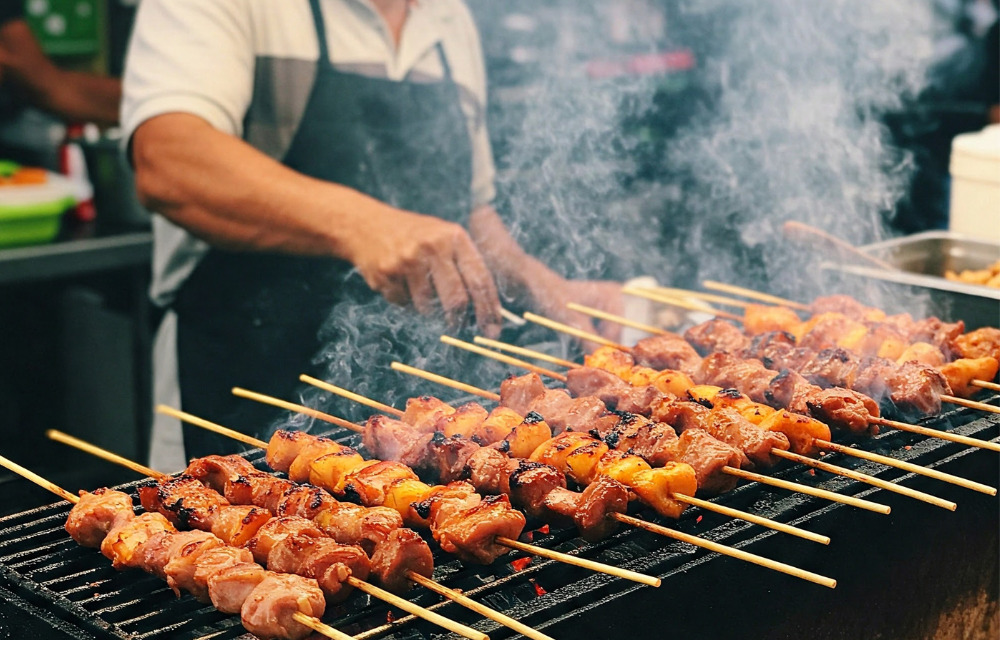 Street food vendor grilling skewers at Sukhumvit Soi 85