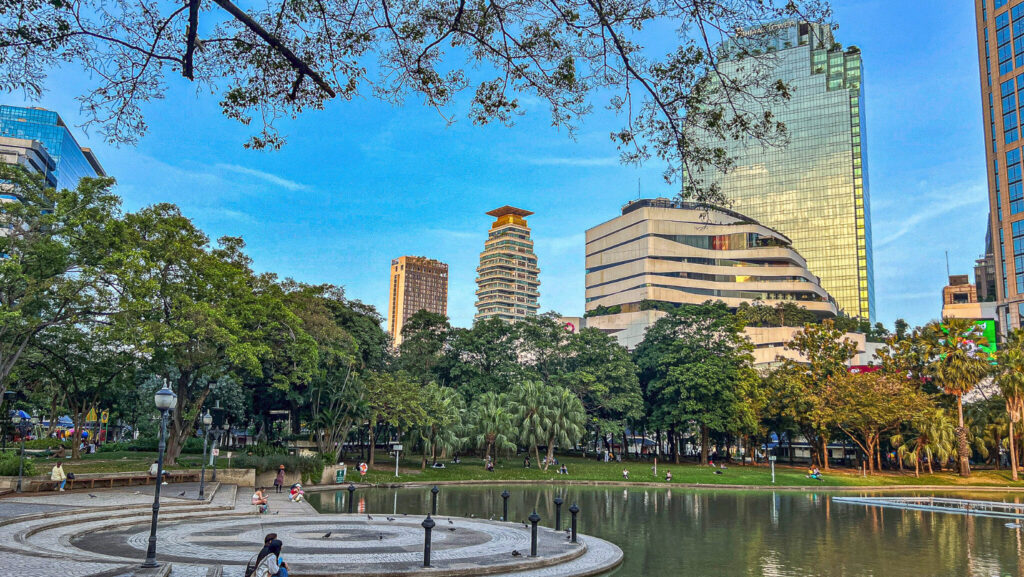 Benjasiri Park Bangkok pond and walking area with city skyscrapers on Sukhumvit Road