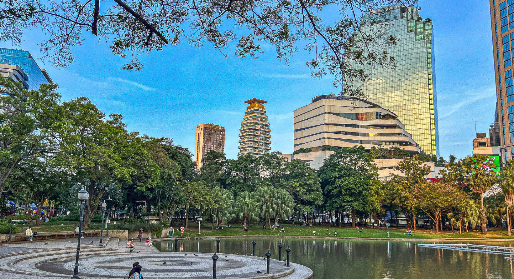 Benjasiri Park Bangkok pond and walking area with city skyscrapers on Sukhumvit Road