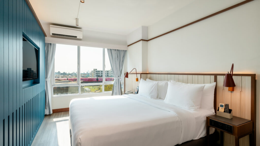 Modern guest room at Hotel Amber Sukhumvit 85 in Bangkok with king-size bed, city view window, and cozy design