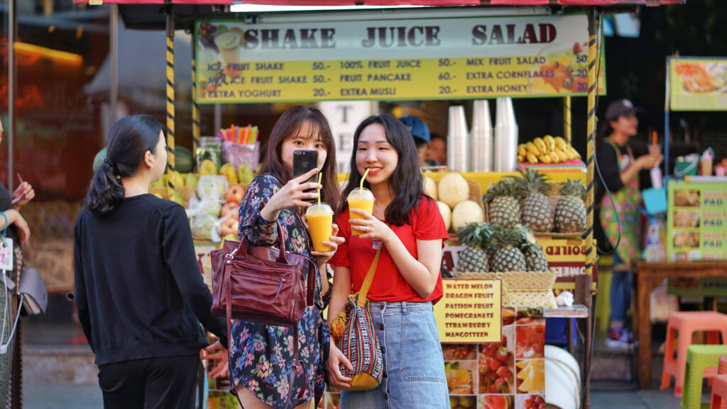 Tourists enjoying fruit shakes at Khaosan Road night market Bangkok
