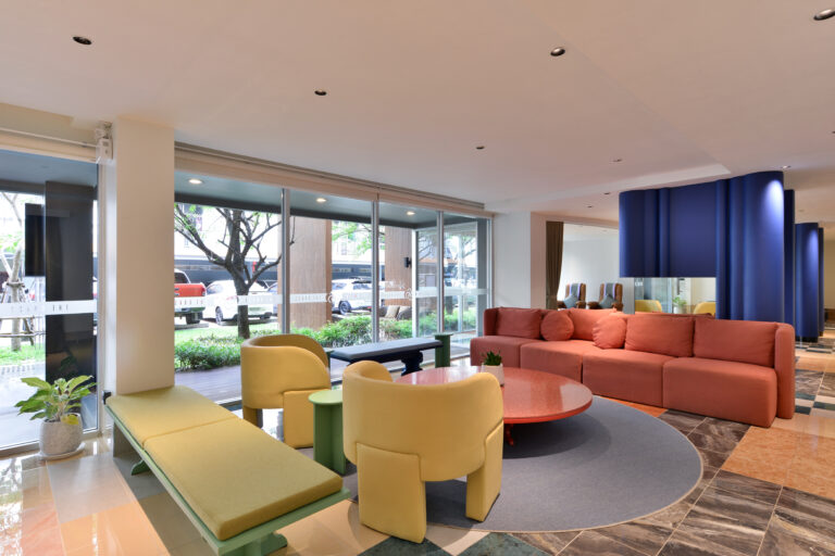 Modern and inviting hotel lobby with colorful furniture, large windows offering natural light, and a welcoming atmosphere.