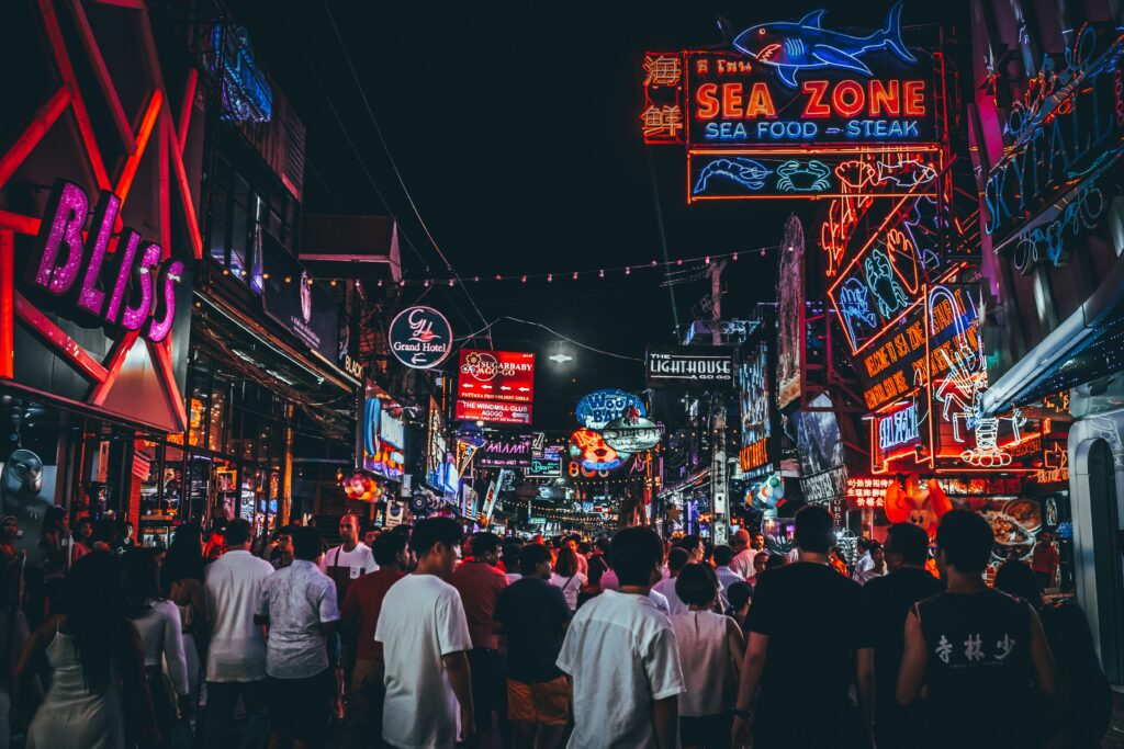 บรรยากาศยามค่ำของถนนคนเดินพัทยาที่เต็มไปด้วยนักท่องเที่ยวและป้ายไฟนีออนจากร้านค้าและคลับ