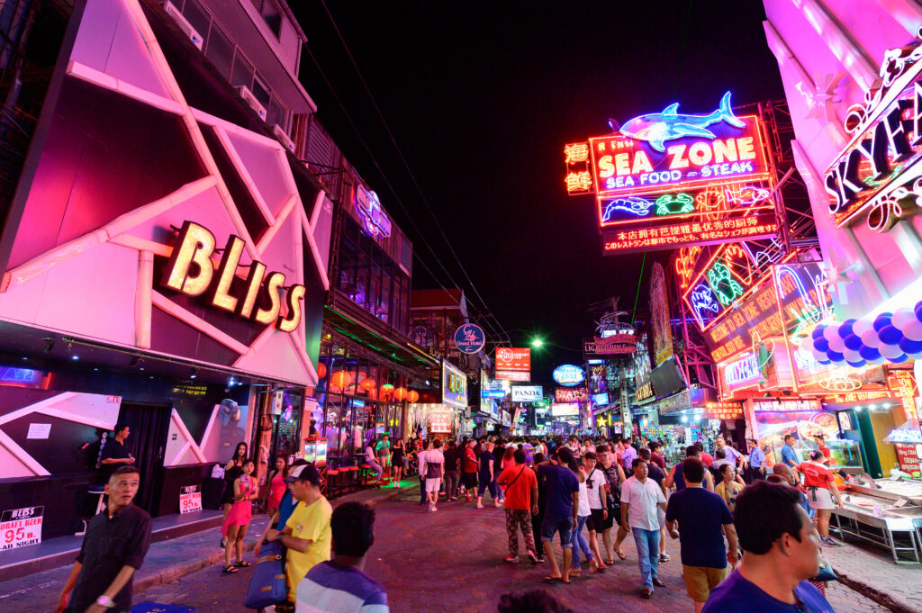 A vibrant scene of Walking Street Pattaya at night, filled with colorful neon signs and crowds of people enjoying the nightlife. The street features popular bars, nightclubs, and restaurants, creating a lively atmosphere.