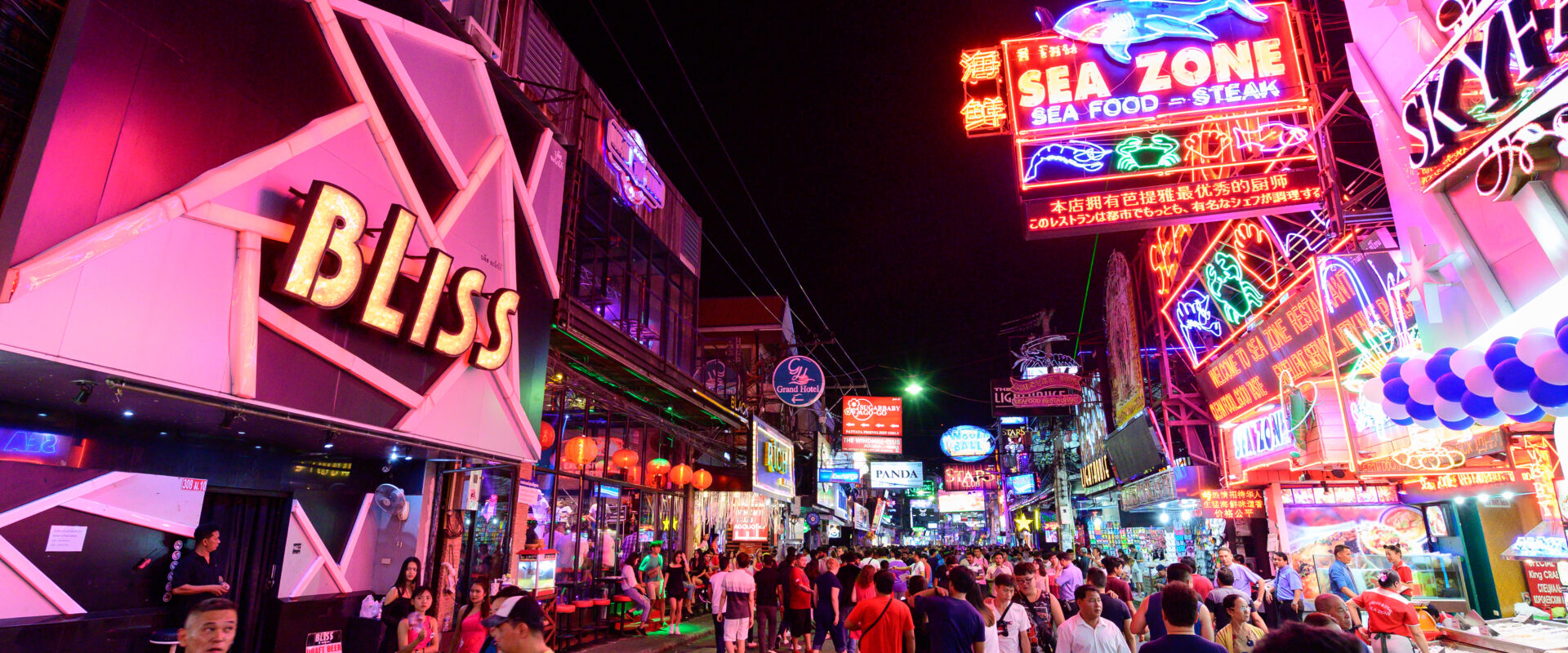 A vibrant scene of Walking Street Pattaya at night, filled with colorful neon signs and crowds of people enjoying the nightlife. The street features popular bars, nightclubs, and restaurants, creating a lively atmosphere.