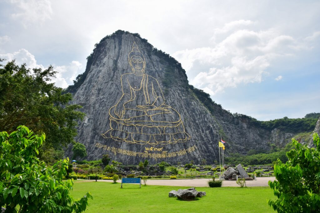 Khao Chi Chan Buddha Mountain in Pattaya featuring a large golden Buddha engraving on a limestone cliff surrounded by gardens and greenery.